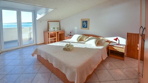 A bedroom with a large bed, a nightstand, a wooden dresser, and a window with a view of the sea. - Apartments Mandre Near sea (Kolan)