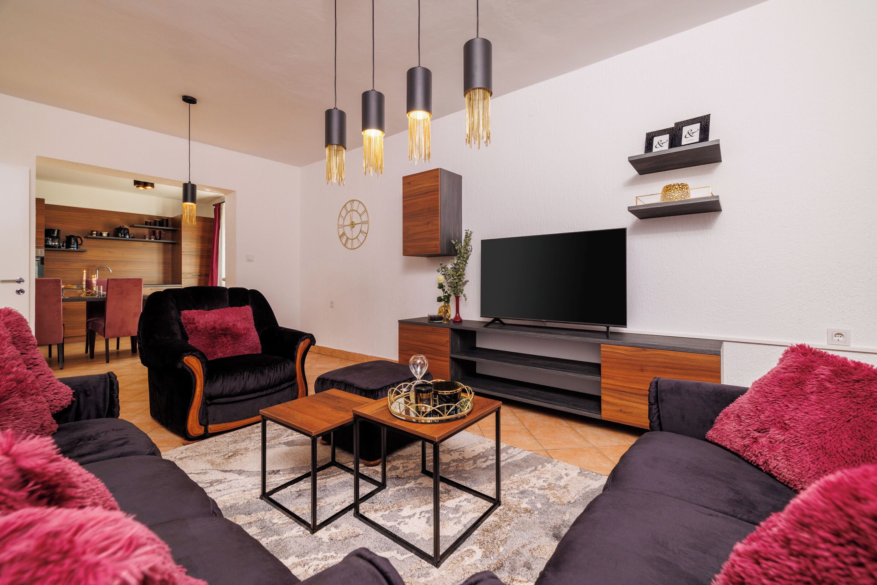 A modern living room with a sofa, a coffee table, a TV, and a kitchen visible in the background.