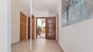 A hallway with wooden flooring, a glass door leading outside, and a painting on the wall. - House Berto (Medulin)
