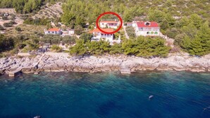 An aerial view of a coastal property with multiple buildings, a rocky shoreline, and clear blue water. - House Ivana (Blato)