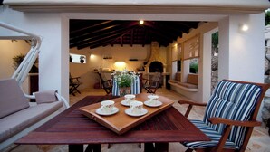 A cozy outdoor dining area with a wooden table set for four, surrounded by comfortable seating. - House Mrcela 200m From Beach (Okrug)