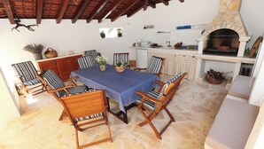 A dining area with a stone fireplace, wooden chairs, and a table set for six. - House Mrcela 200m From Beach (Okrug)