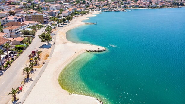 A coastal town with a sandy beach, clear blue waters, and residential buildings along the shore. - House Mrcela 200m From Beach (Okrug)