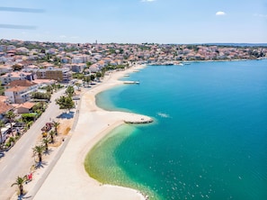 A coastal town with a sandy beach, clear blue waters, and residential buildings along the shore. - House Mrcela 200m From Beach (Okrug)