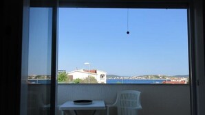 Een balkon met een tafel en twee stoelen, met uitzicht op een kustgebied met gebouwen en een heldere lucht.