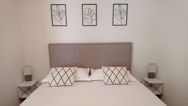 A neatly made bed with two pillows, a headboard, and two bedside tables with lamps. - Apartments Dariana (Makarska)