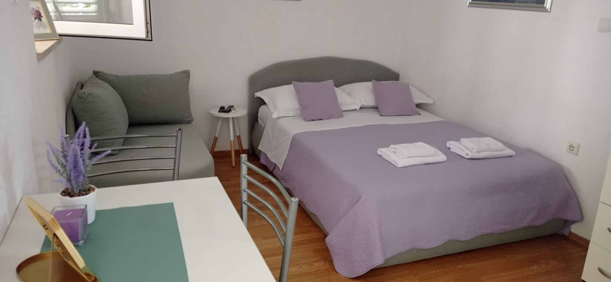 Une chambre bien rangée, avec un lit, une table de chevet et un petit bureau.