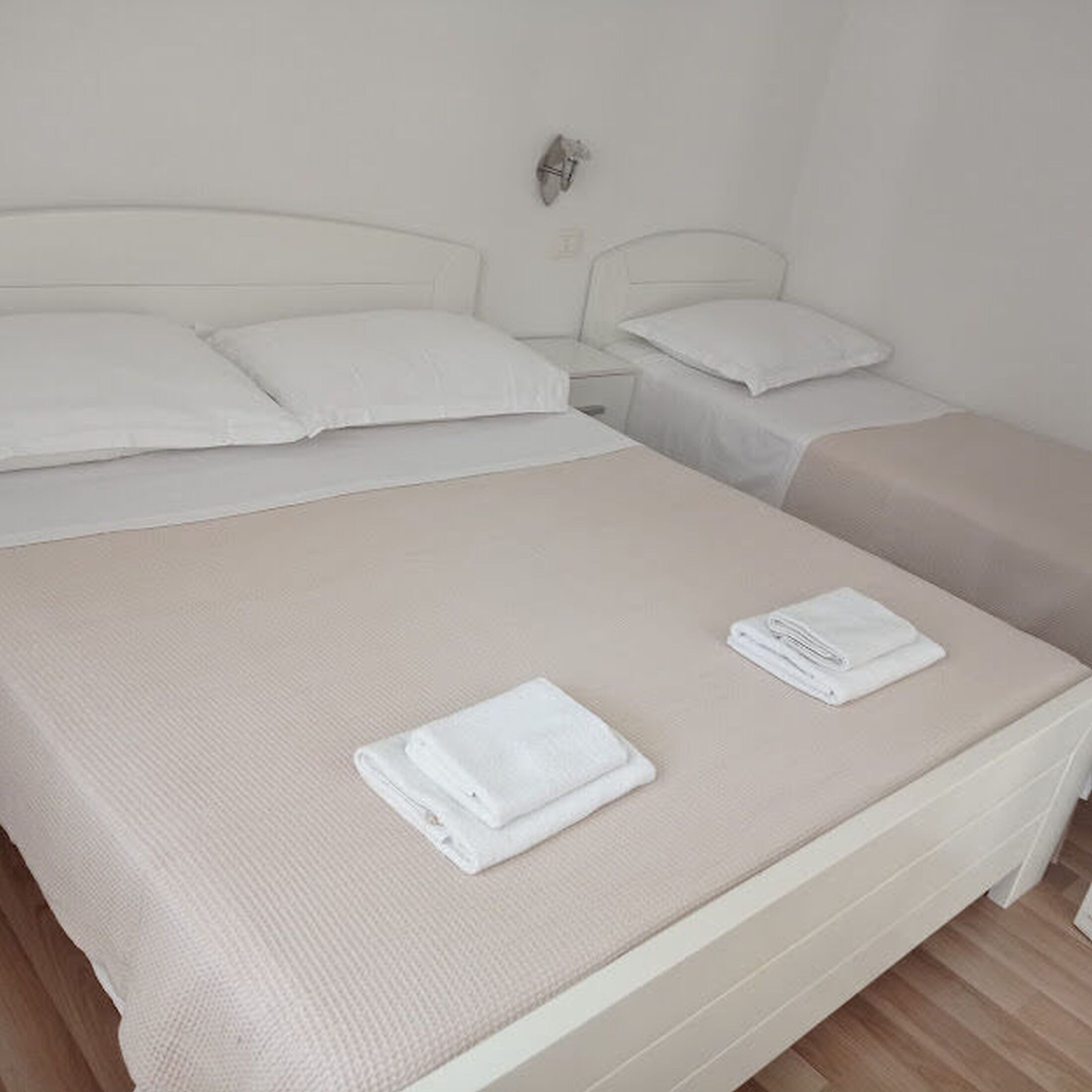 A hotel room with a large bed, a smaller bed, and a nightstand with a lamp.