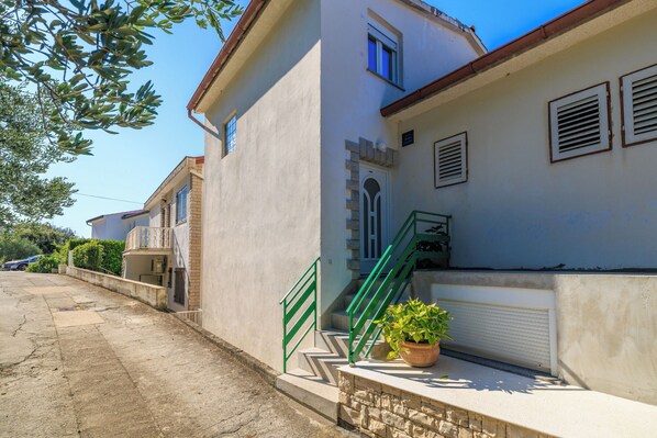 Un edificio residenziale con una scala, una pianta in vaso e un muro in pietra.