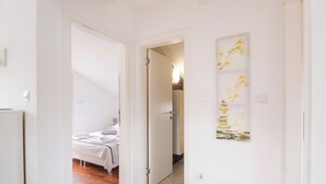Ein Flur, der in ein Schlafzimmer mit Bett, Tür und Wand mit einem Gemälde führt.