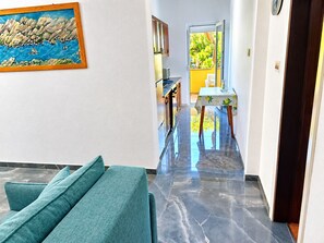 A hallway with a sofa, a painting, and a view into a dining area with a table and chairs. - Apartment Maris (Karlobag)