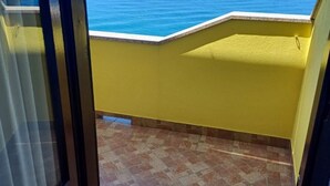 A balcony with a view of the sea, yellow walls, and tiled flooring. - Apartment Maris (Karlobag)