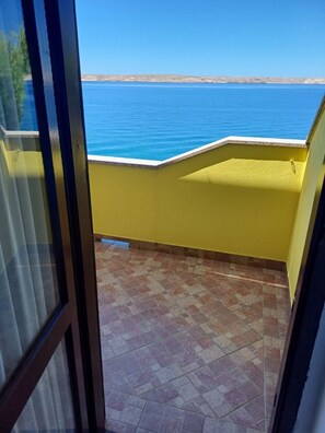 A balcony with a view of the sea, yellow walls, and tiled flooring. - Apartment Maris (Karlobag)
