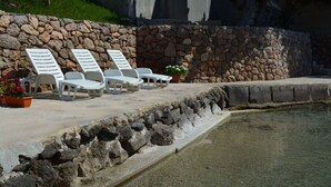 A poolside area with lounge chairs and potted plants. - Apartment Maris (Karlobag)