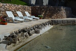 A poolside area with lounge chairs and potted plants. - Apartment Maris (Karlobag)