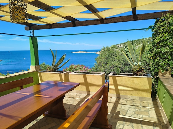 A wooden bench and table under a pergola with a view of the sea and distant island. - House Villa Carmen (Rogoznica)