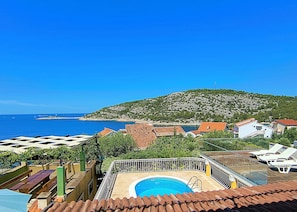 A pool area with a view of the sea and a hill in the background. - House Villa Carmen (Rogoznica)