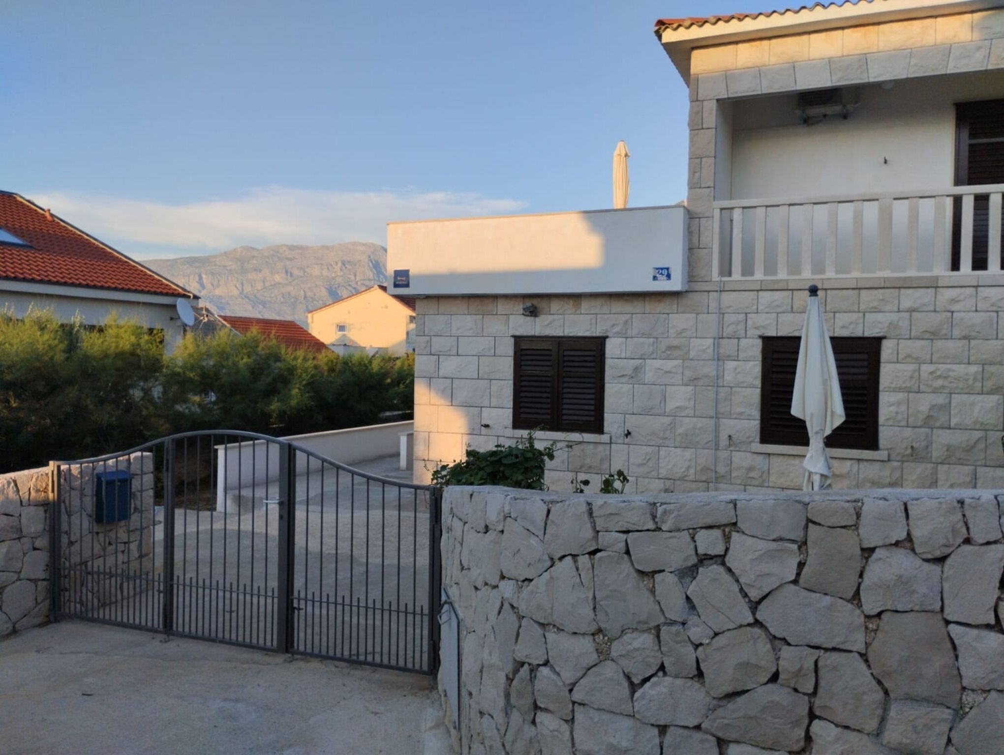 Una casa de piedra con entrada porticada, un balcón y montañas al fondo.
