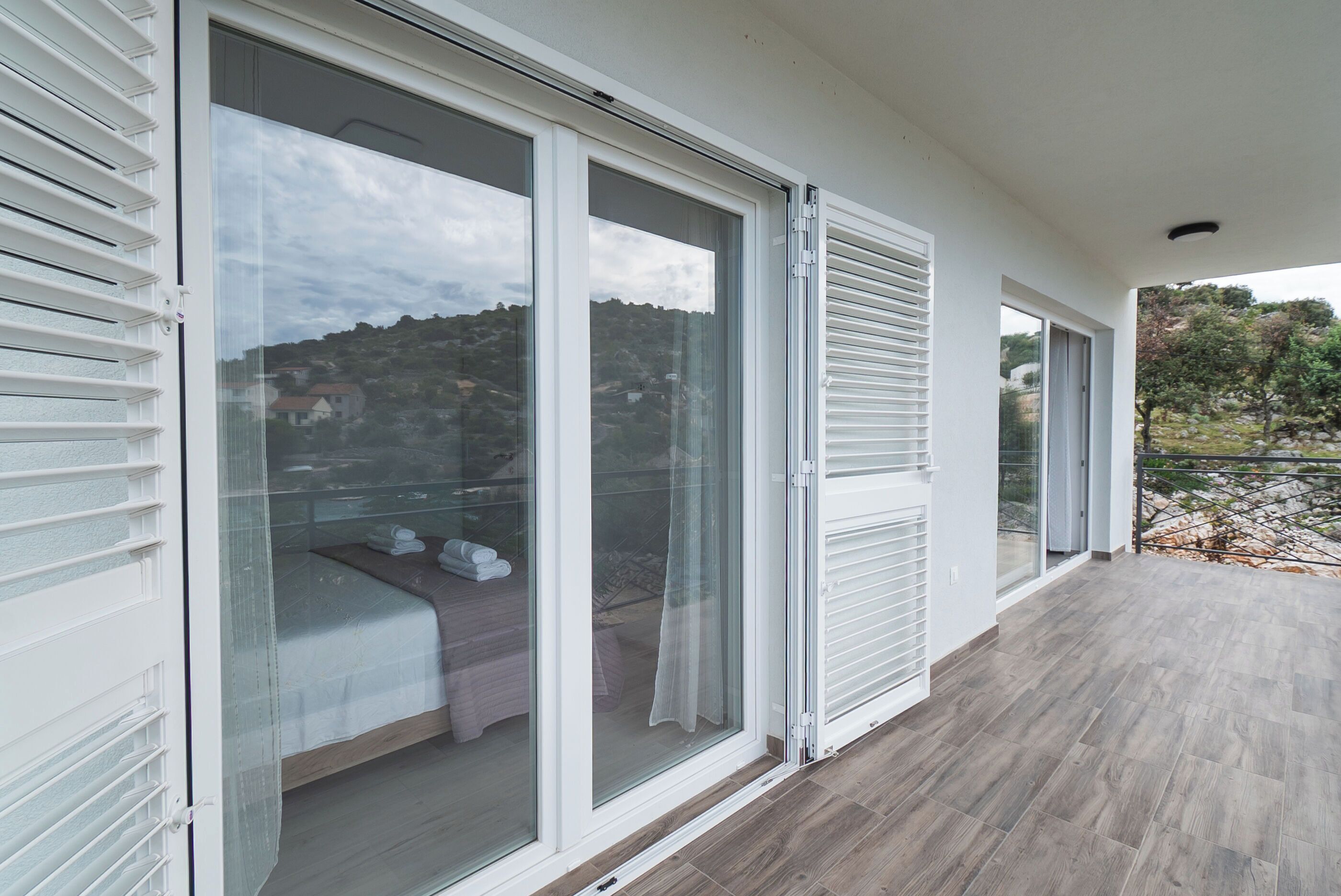 A balcony with a bed and a view of a hilly landscape.