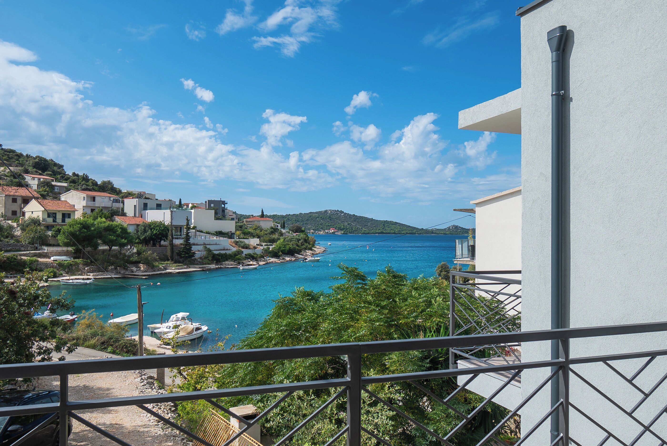 A coastal town with buildings overlooking a bay, a clear sky, and a view of boats.