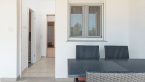 Una habitación con una mesa de comedor y sillas, una ventana con cortinas, y una puerta que da a otra estancia.