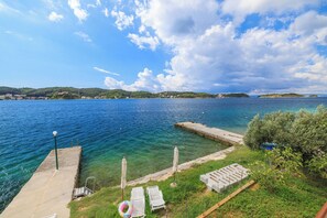 Un molo che si protende in un mare blu e limpido, con un'area verde e sdraio.