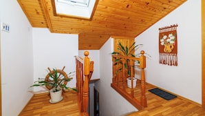 Eine Holztreppe mit Oberlicht, Zimmerpflanzen und einer Wandteppich.
