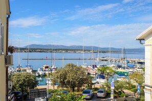 Un port de plaisance avec des bateaux amarrés, un ciel dégagé et une chaîne de montagnes à l’horizon.