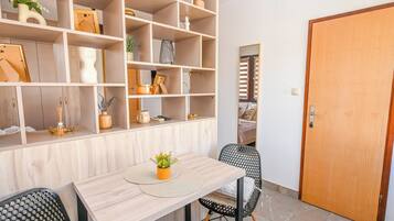 A room with a wooden dining table, chairs, a bookshelf, and a door.