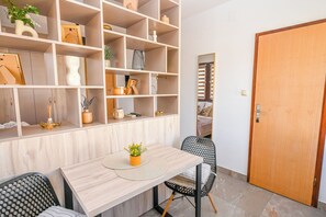 Une pièce comprenant une table à manger en bois, des chaises, une bibliothèque et une porte.