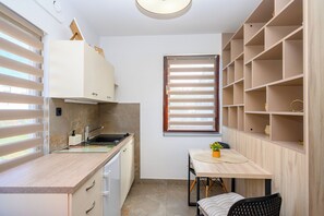 Una cocina compacta con un lavamanos, armarios y una ventana con persianas.