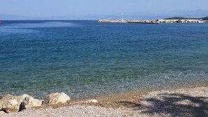 A coastal view with clear water, a rocky shoreline, and a distant pier. - Apartment Neo (Malinska-Dubasnica)