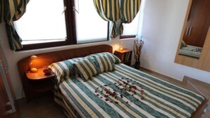 A bedroom with a bed, a nightstand, a lamp, a window with curtains, and a wardrobe. - Apartment Neo (Malinska-Dubasnica)