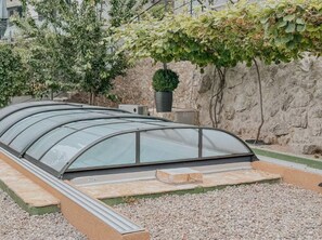 A greenhouse structure with a curved glass roof, surrounded by gravel and a stone wall. - House Mili (Zagvozd)