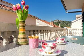 Ein Balkon mit Tisch, gedeckt für Tee, einer Vase mit Tulpen und einer Zierbecher.
