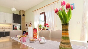 Una cocina moderna con horno empotrado y comedor con mesa dispuesta para el desayuno.