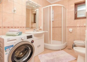 Ein modernes Badezimmer mit Waschmaschine, Waschbecken, Dusche und Toilette.