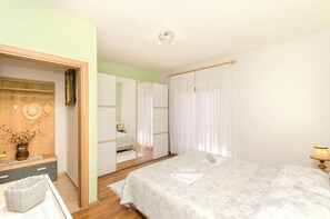 Ein Schlafzimmer mit einem Bett, einem Nachttisch, einer Lampe, einem Spiegel und einem Kleiderschrank.