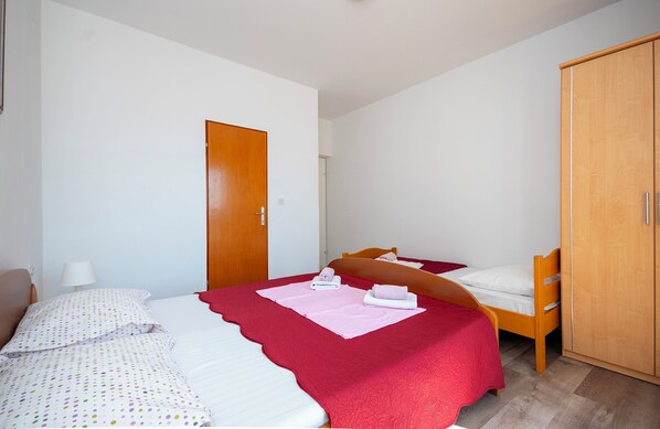 A bedroom with two beds, a wardrobe, and a door.