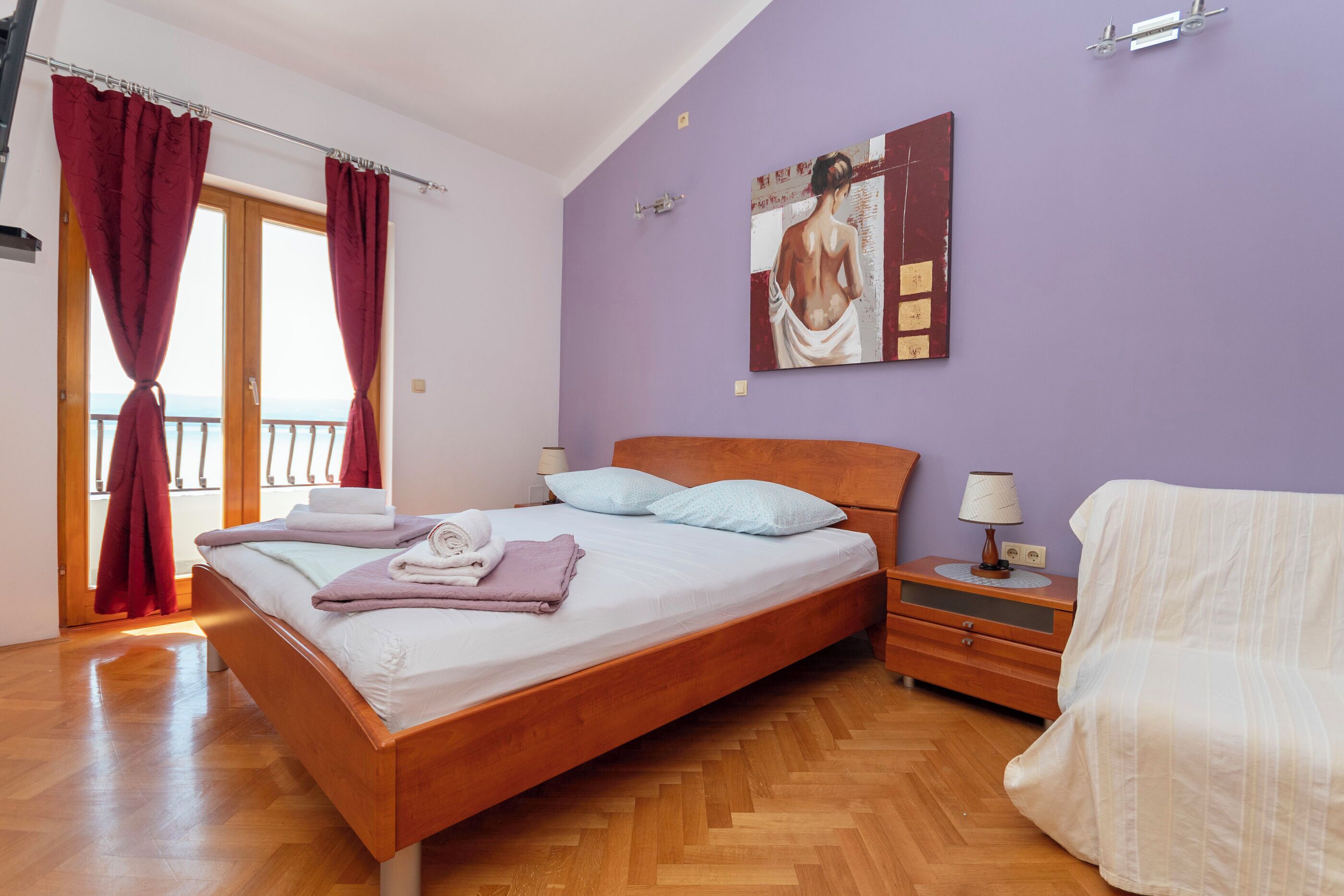 Un dormitorio con una cama de madera, una mesita de noche, una lámpara y un cuadro en la pared.