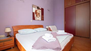 A bedroom with a bed, nightstands, a wardrobe, and a painting on the wall.