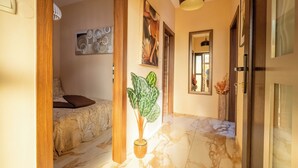 A hallway with a bed, a potted plant, and a mirror. - Apartments Relax Suites (Novi Vinodolski)