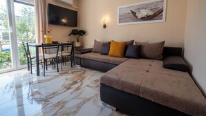 A modern living room with a sectional sofa, a dining table with chairs, and a large window with curtains. - Apartments Relax Suites (Novi Vinodolski)