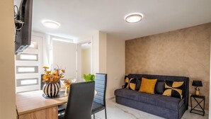 A modern living room with a sofa, a dining table, and a chair. - Apartments Relax Suites (Novi Vinodolski)