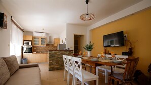 A modern kitchen with a stone backsplash, wooden cabinets, and a dining area with a table set for four. - House Dragica (Vinodol)