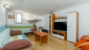 A cozy living room with a sofa, a coffee table, a TV, and a cabinet. - Apartment Lili (Umag)