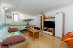 Ein gemütliches Wohnzimmer mit Sofa, Couchtisch, Fernseher und Schrank.