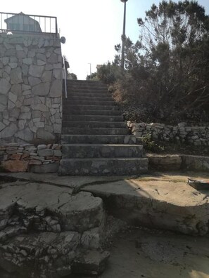 Eine Steintreppe führt zu einem Gebäude, gesichert durch ein Metallgeländer.