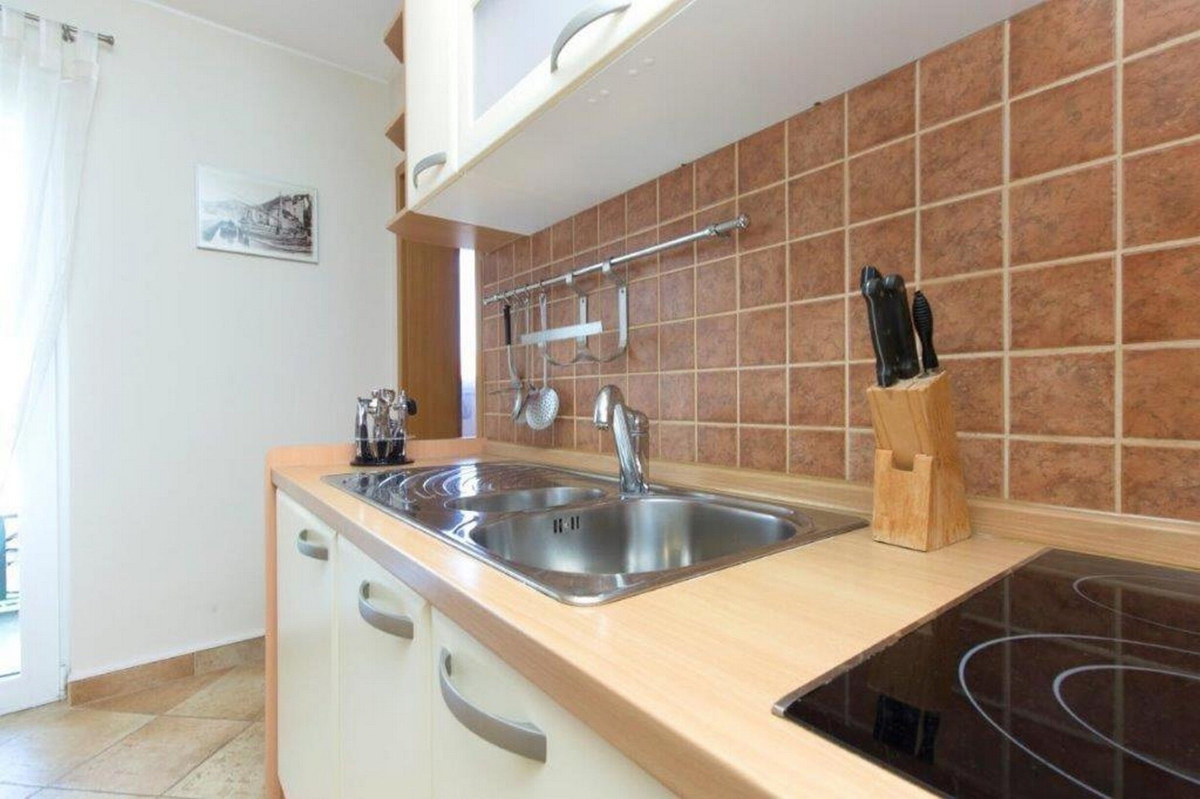 A kitchen with a double sink, a stove, and a knife block.