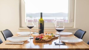 Une table à manger avec une planche à fromage, des verres à vin et une bouteille de vin.